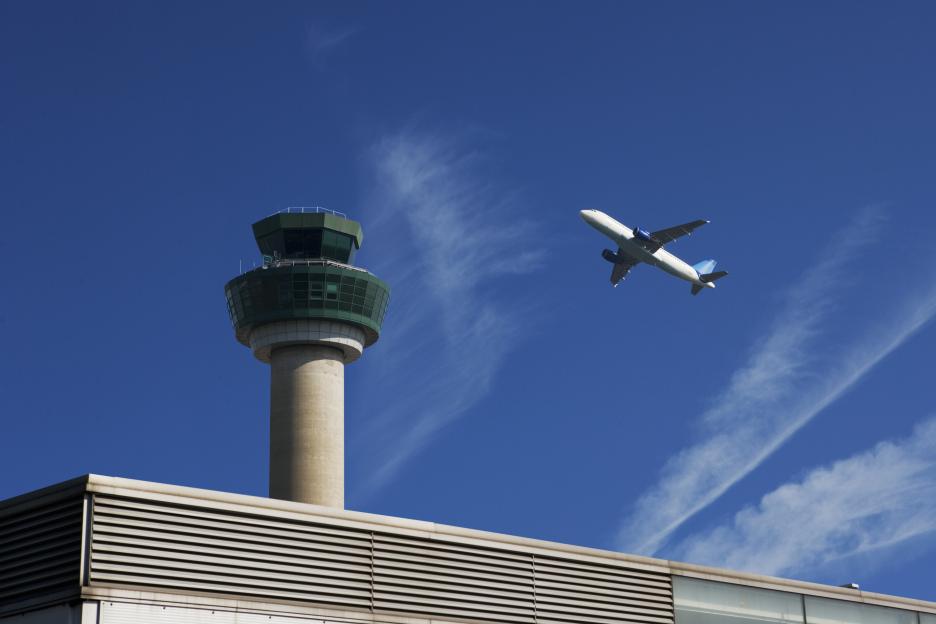 Airplane taking off near air traffic control tower.