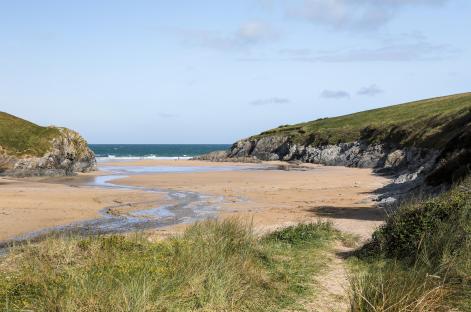 Sandy beach cove between two cliffs in Cornwall.