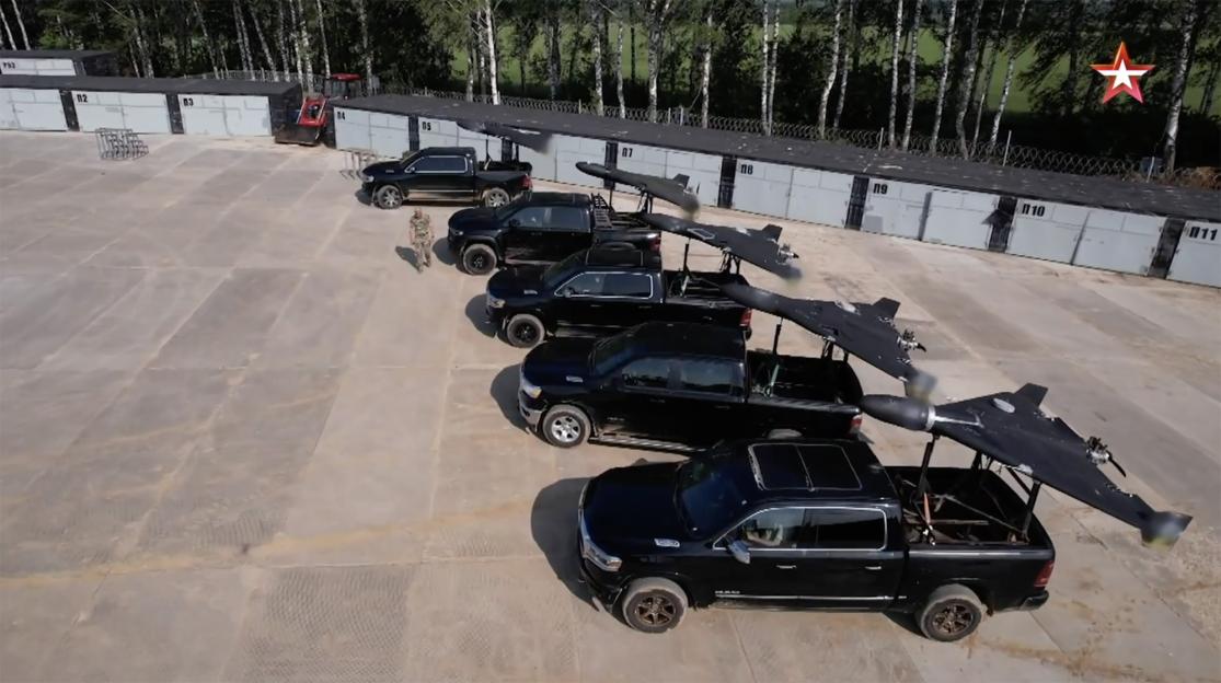 Several black pickup trucks with Geran-2 drones in their beds.