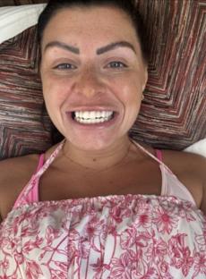 Close-up of a woman smiling, showing off her new teeth.