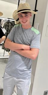 Photo of Jay Slater wearing a gray shirt and shorts, and a straw hat.