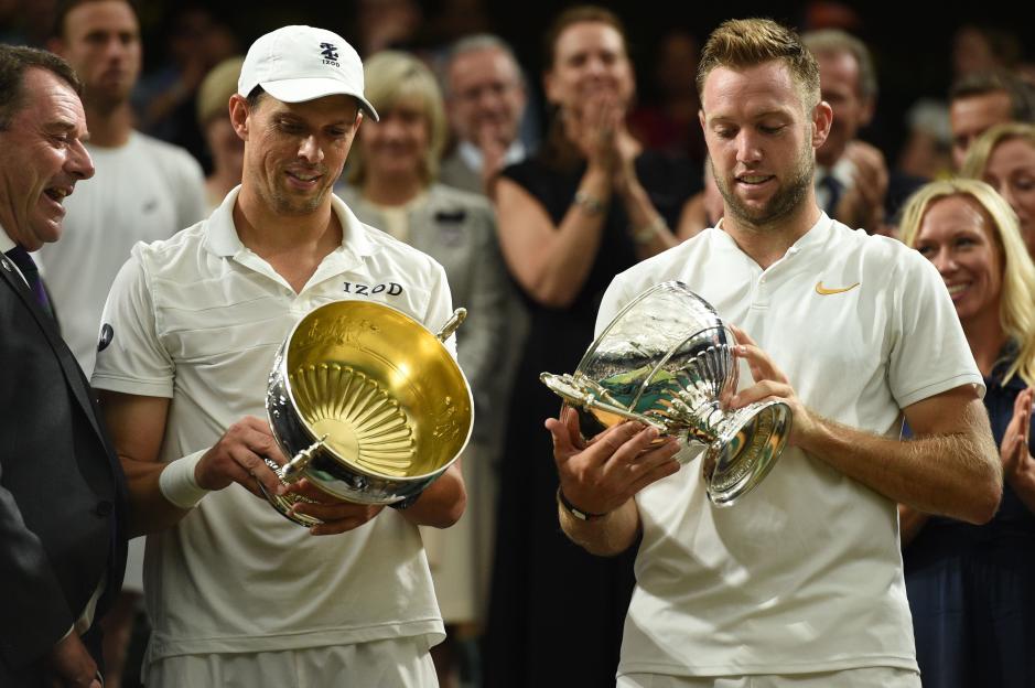 Two tennis players holding trophies after winning a doubles match at Wimbledon.