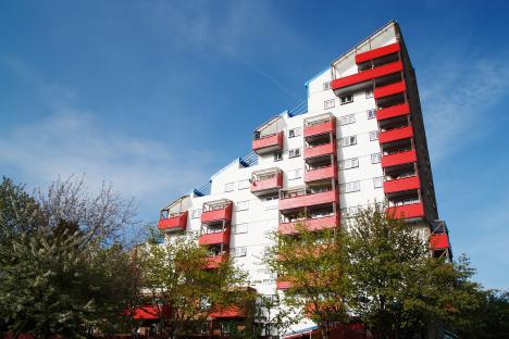 Apartment building with red balconies against a blue sky.