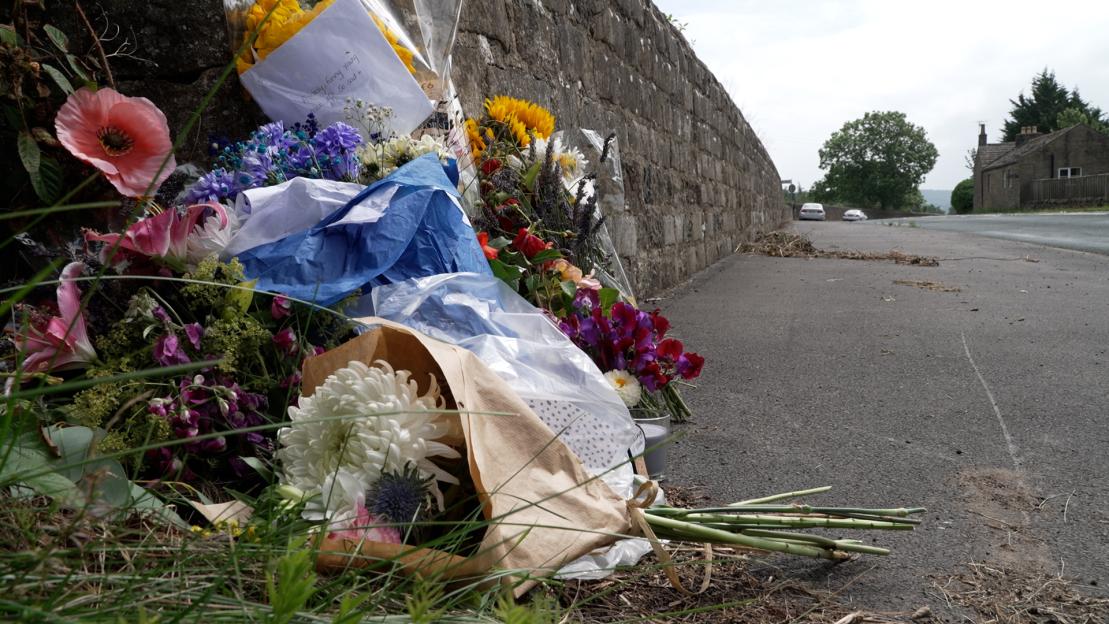 Flowers and a note left at a roadside memorial.