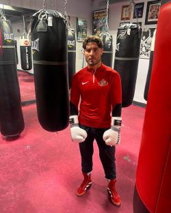 Man in boxing gear standing in a gym.