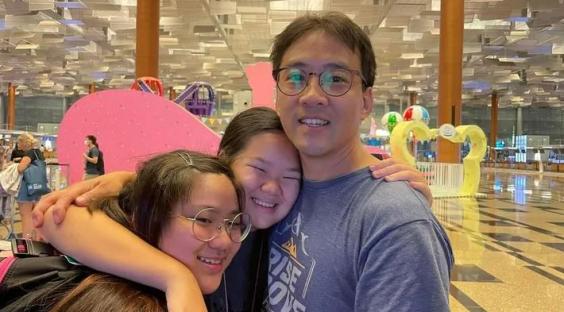 A father embracing his two daughters at an airport.