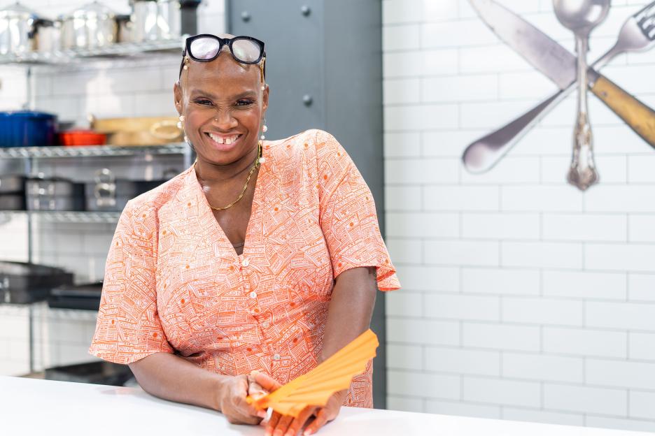 Andi Oliver, chef, smiling in a kitchen.