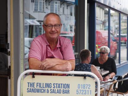 The owner of The Filling Station sandwich and salad bar stands outside his shop.