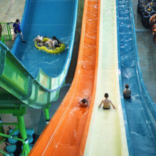 Aerial view of people sliding down multiple water slides at a water park.