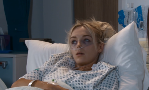 Screenshot of a young woman lying in a hospital bed.