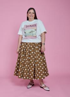 Woman in white graphic tee and brown polka dot skirt.