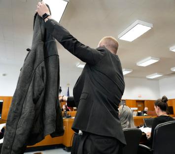 Prosecutor holding up a jacket containing DNA evidence in court.