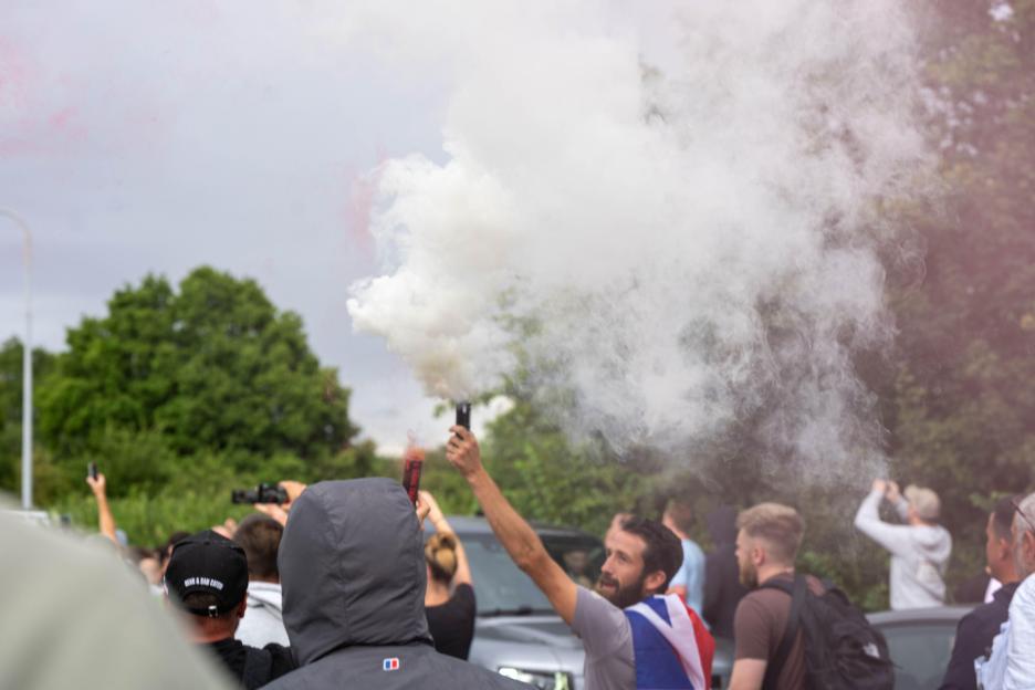 A person ignites a smoke flare at a protest.