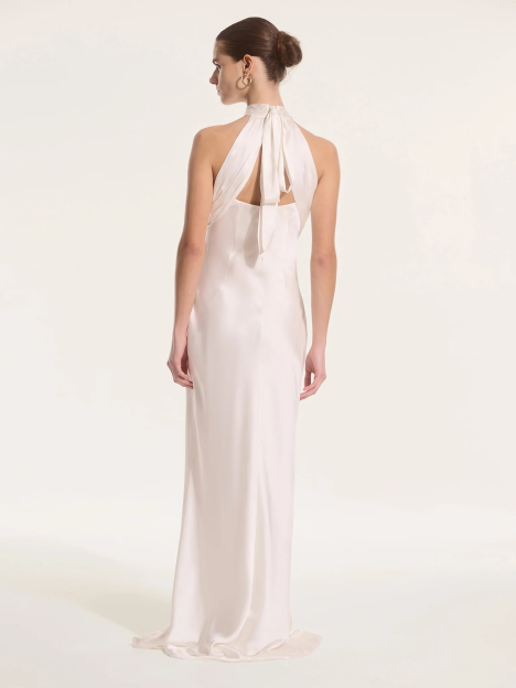 Woman in a long, light pink halter neck dress.