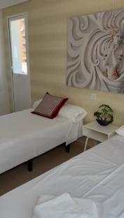 Bedroom with two twin beds, a white nightstand, and wall art.