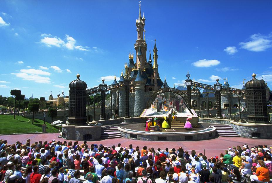 A large crowd watching a performance in front of Sleeping Beauty Castle at Disneyland Paris.