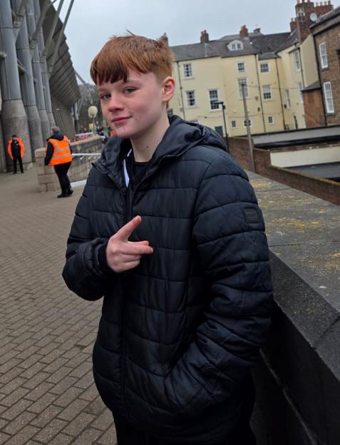 Teenager in a black puffer jacket, possibly after inhaling a spice-laced vape.