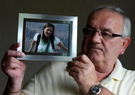 A man holding a photograph of his missing daughter.