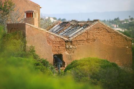 A person inspecting a dilapidated building.