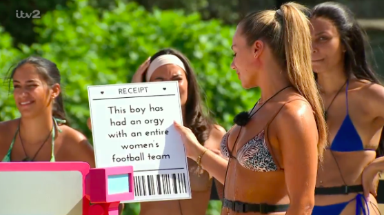 Screenshot of a woman holding a sign that reads