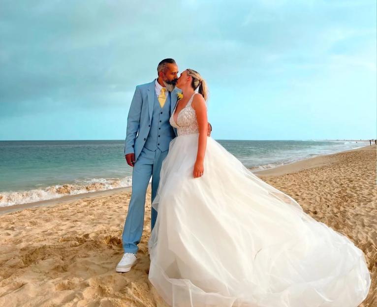 Bride and groom kissing on a beach.