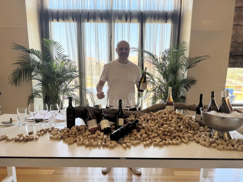 Man holding wine bottles surrounded by wine corks.