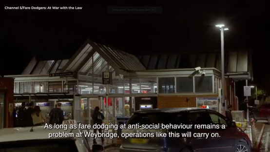 Screenshot of a nighttime scene at Weybridge station with people and cars.