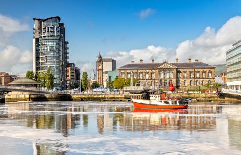 Long exposure photo of the Lagan River in Belfast, with the Custom House and other buildings reflected in the water.