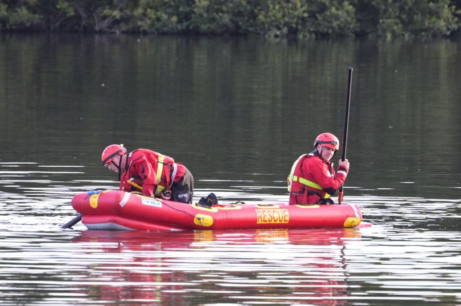 Rescue workers in a boat searching a lake.
