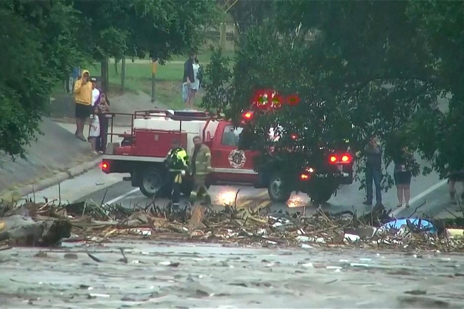 First responders assess floodwaters and debris near a firetruck.