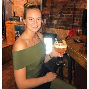 Woman holding a cocktail in a bar.