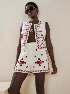 Model wearing an embroidered cream-colored vest and shorts.