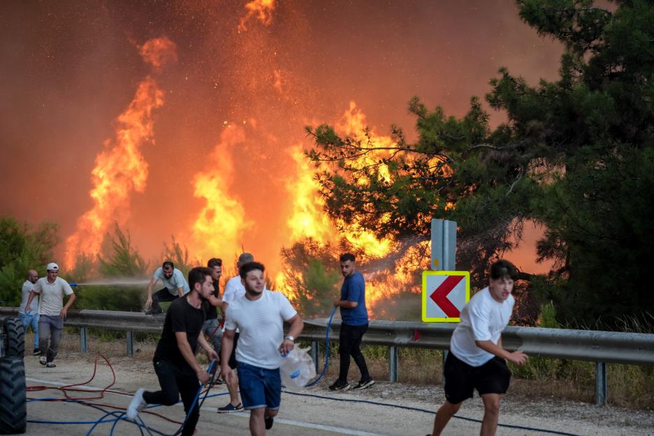 Firefighters and civilians battling a large forest fire.