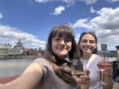 Two women enjoying wine with London skyline in the background.
