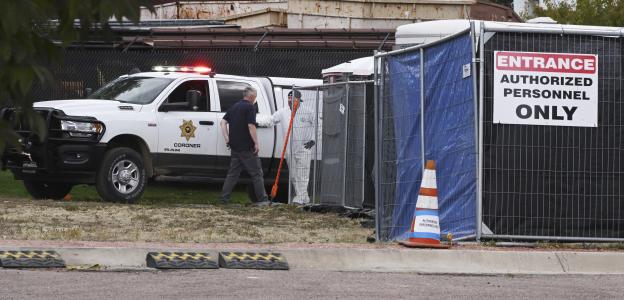 Coroner's office workers processing remains outside a temporary structure.