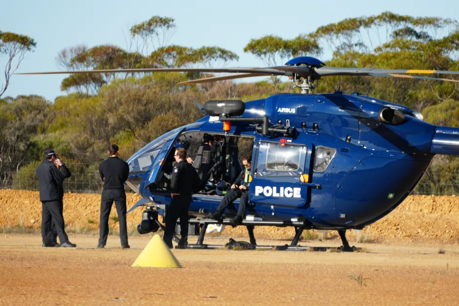 Police helicopter on the ground with officers nearby.