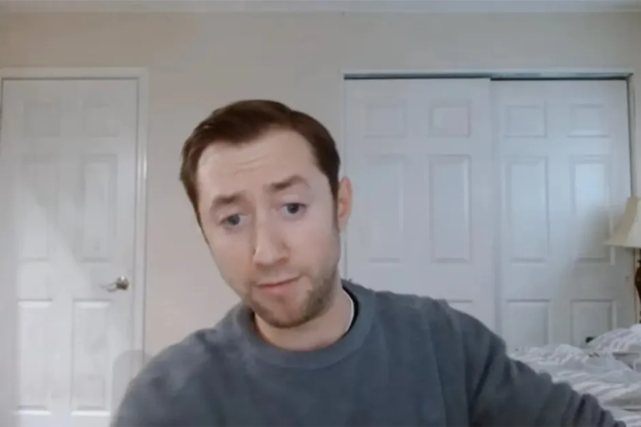 Man in gray sweater during a video call.