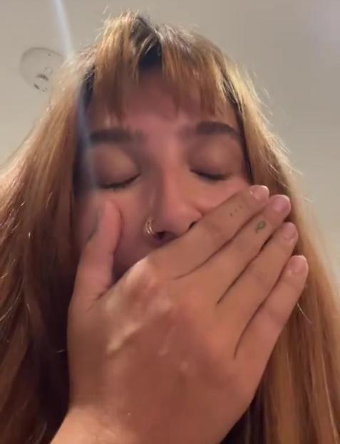Woman covering her mouth with her hand, eyes closed.