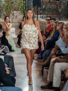 Lexi Hughes modeling a white floral dress at London Fashion Week.