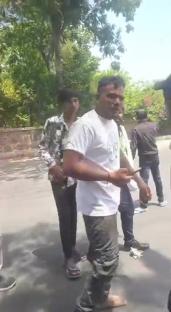 Man calmly walking away from a large fire, while others rush to help.