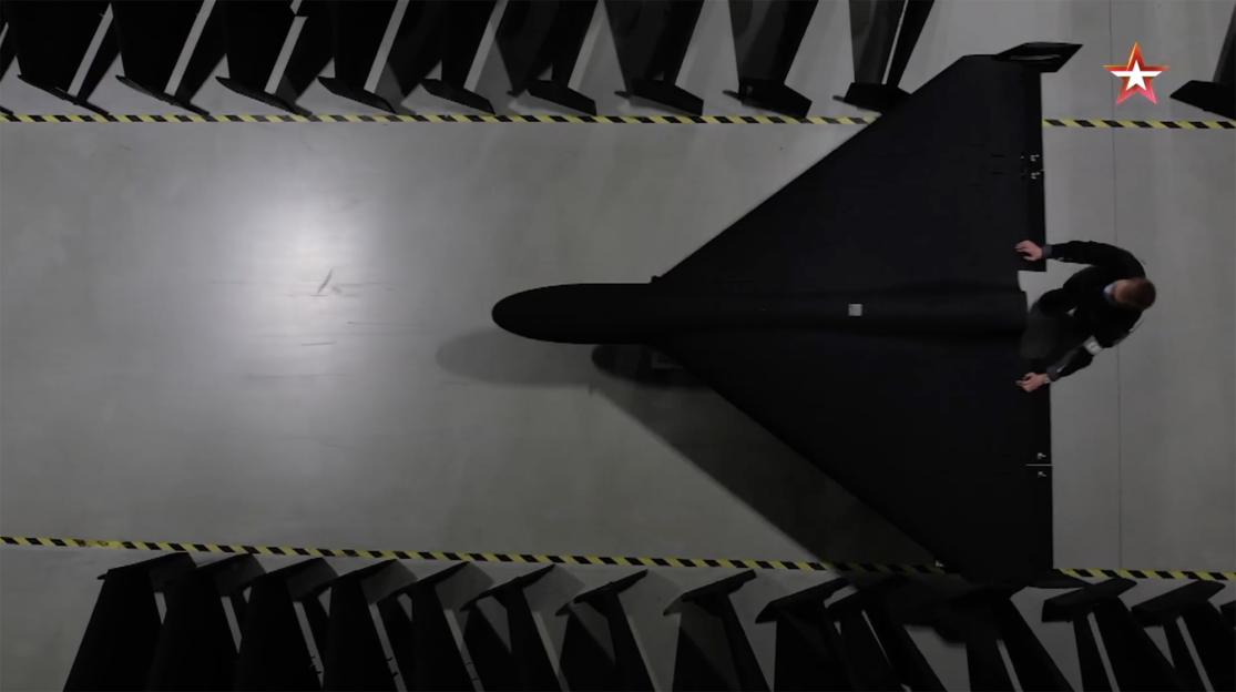 Overhead view of a person assembling a black Geran-2 drone in a factory.