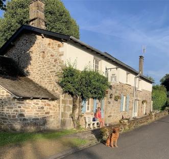 Woman sitting outside a French bed and breakfast with her dog.
