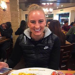 Woman in a Nike vest sitting at a restaurant table.