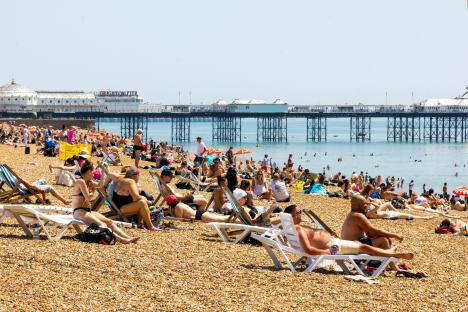 Crowded Brighton beach with the pier in the background.