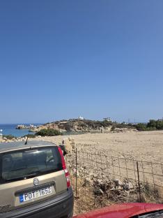 Car parked near a beach with a small white church on a hill in the background.
