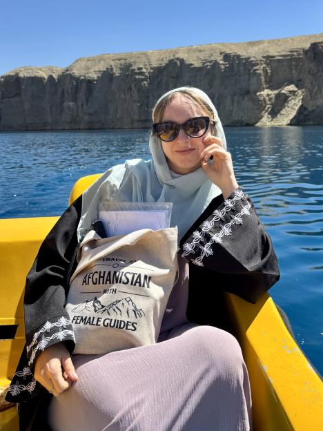 Woman in sunglasses and headscarf sits in a yellow boat on a lake in Afghanistan.