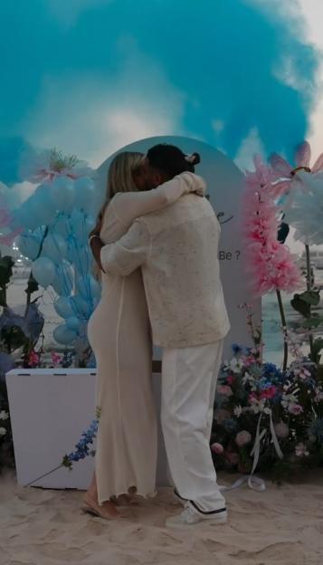 Couple embracing at a gender reveal party.