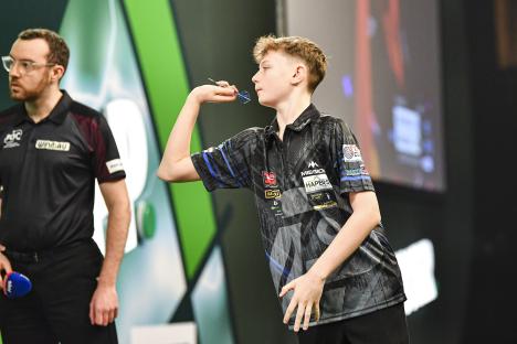 Teenage darts player throwing a dart.