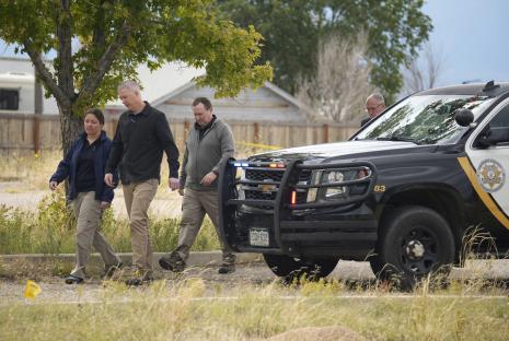 Investigators walk near a police vehicle at a funeral home where numerous bodies were found.