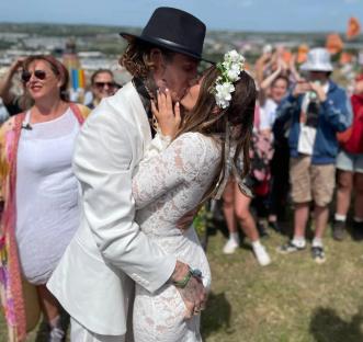 Couple kissing at a wedding ceremony with a large crowd cheering.